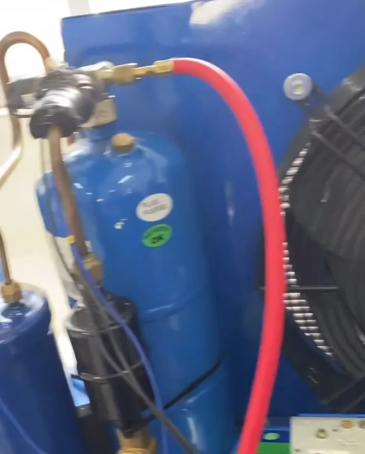 Compressor azul de uma câmara fria com tubulação de cobre e mangueira vermelha