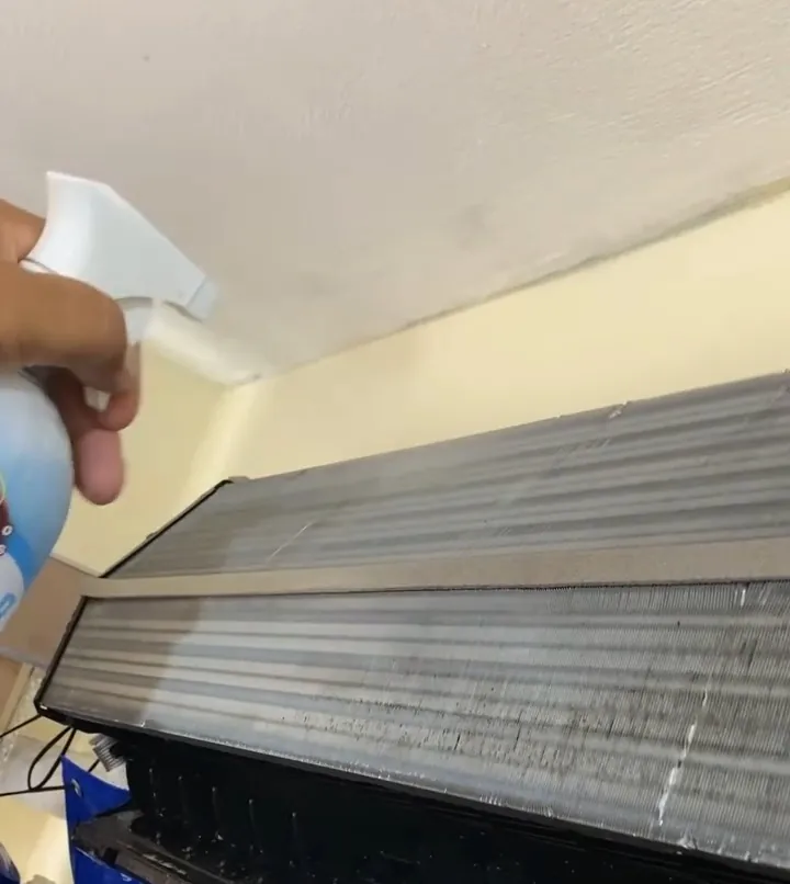 Aplicação de produto de limpeza na serpentina de um ar condicionado aberto