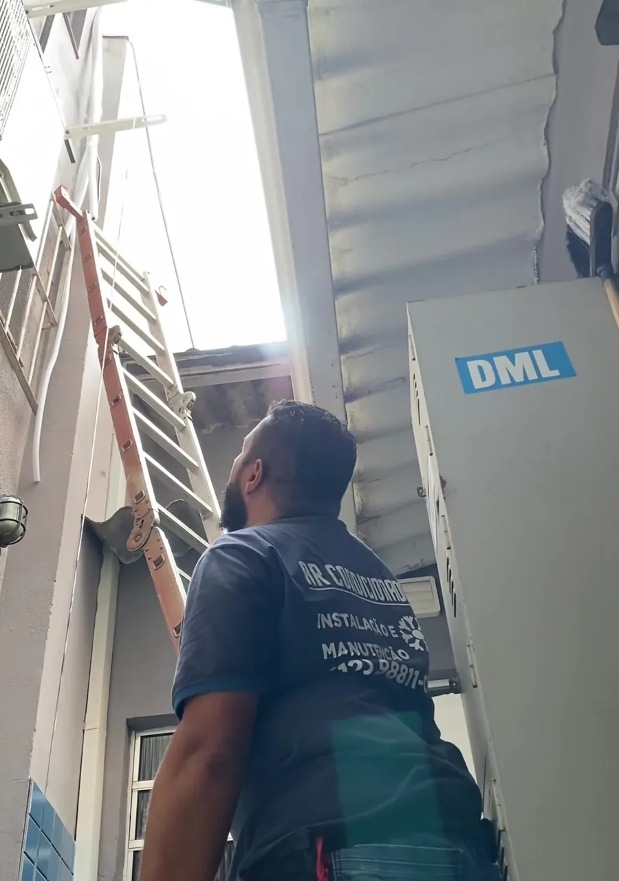 Técnico subindo uma escada encostada no prédio para instalar uma condensadora no alto