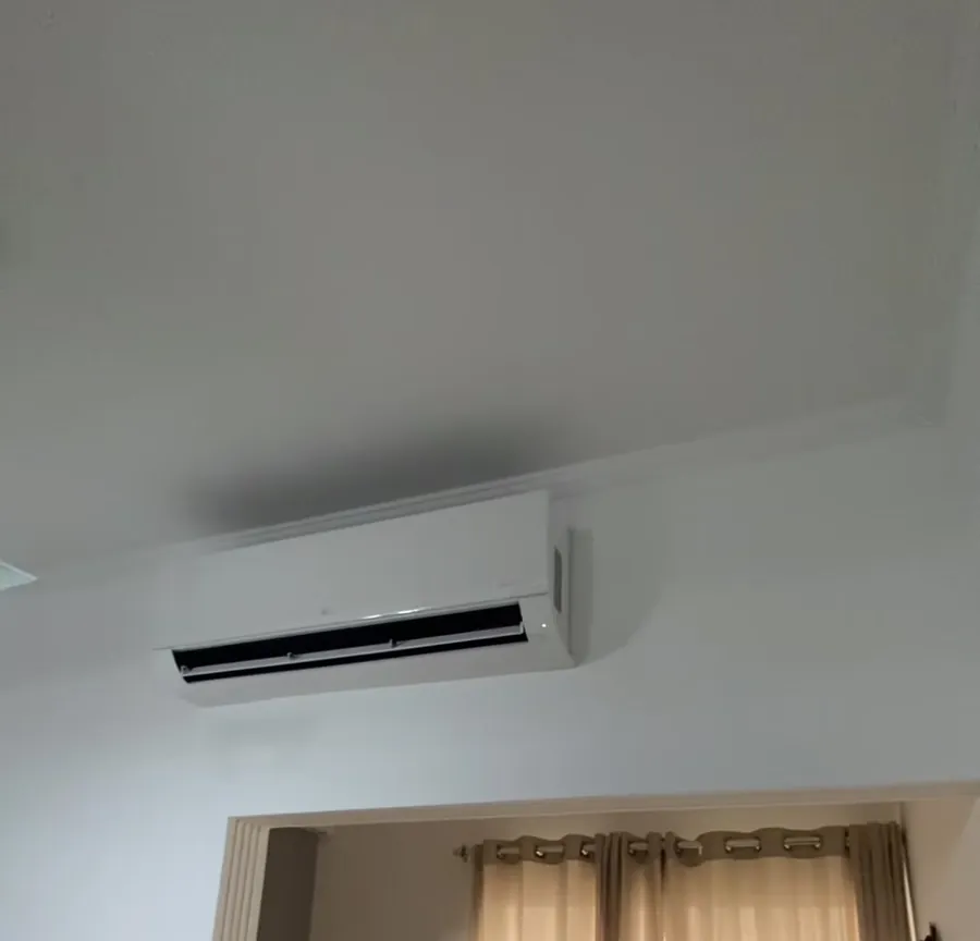 Ar condicionado split instalado no alto da parede, acima de uma porta de madeira