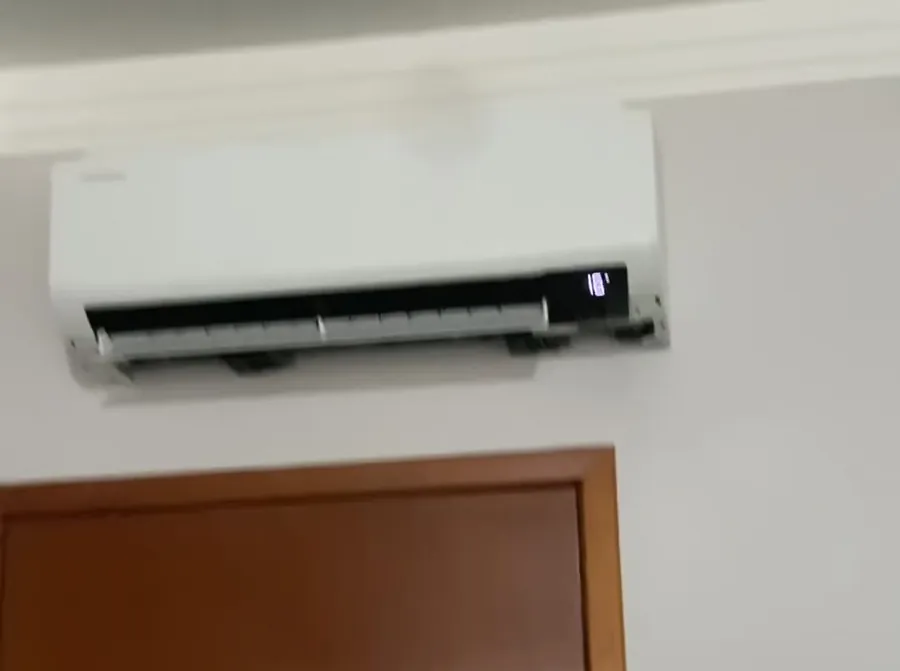 Split instalado acima da porta de um quarto com acabamento branco